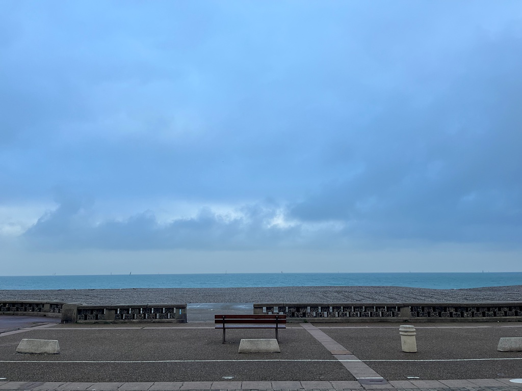 An image of the beaches in Dieppe, Normandy, France in autumn with an empty bench