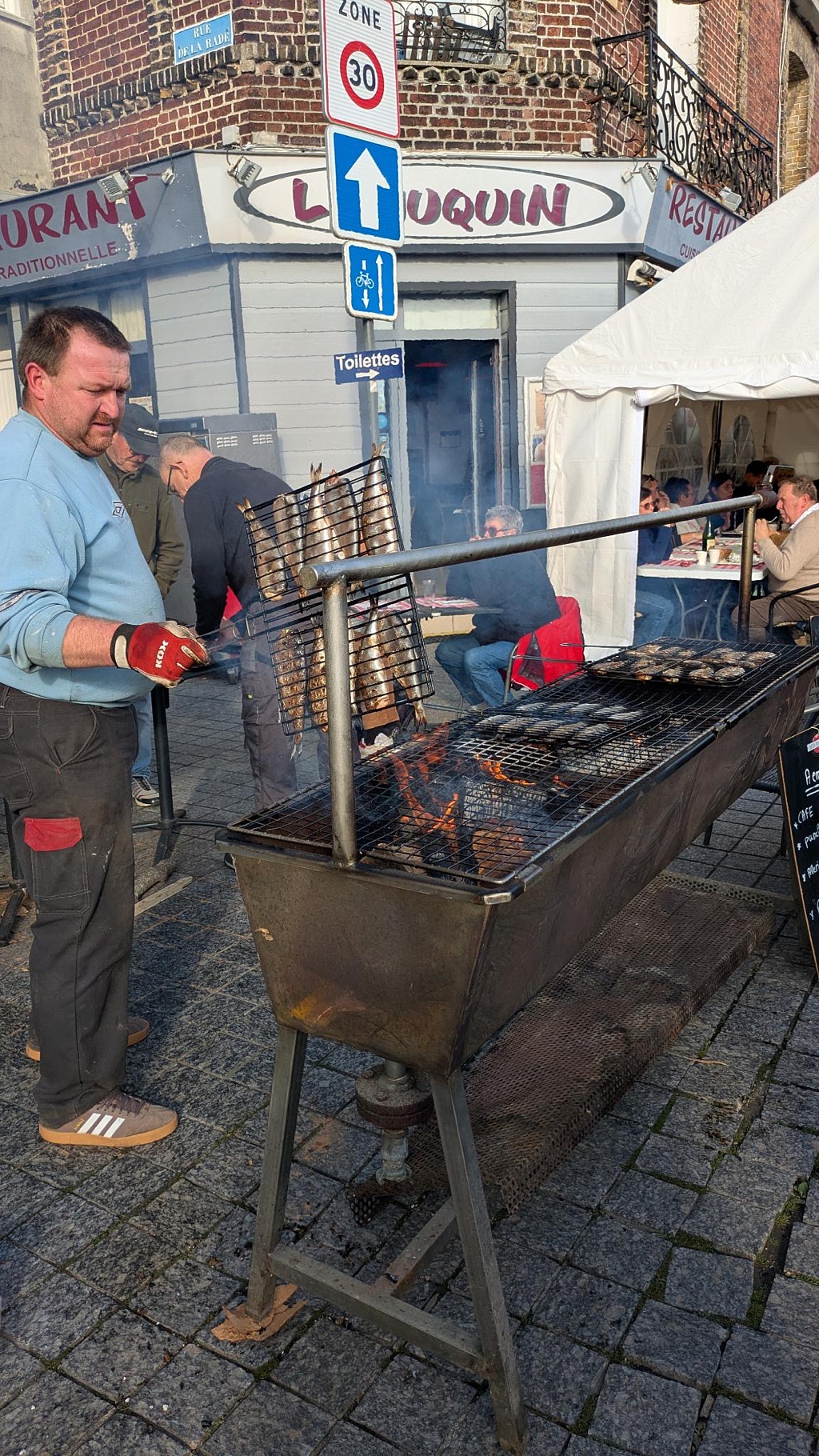 A man grills herring over an open flame in Dieppe, France in the Normandy region
