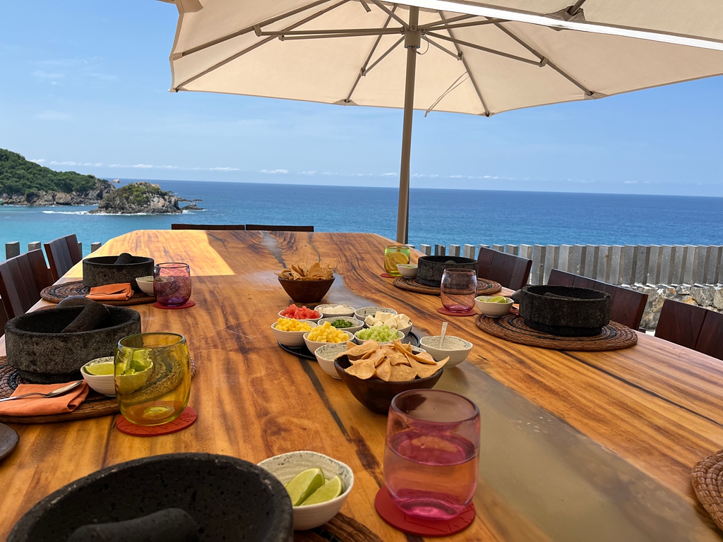 A table with ocean view set up for guacamole class with plates and fixings
