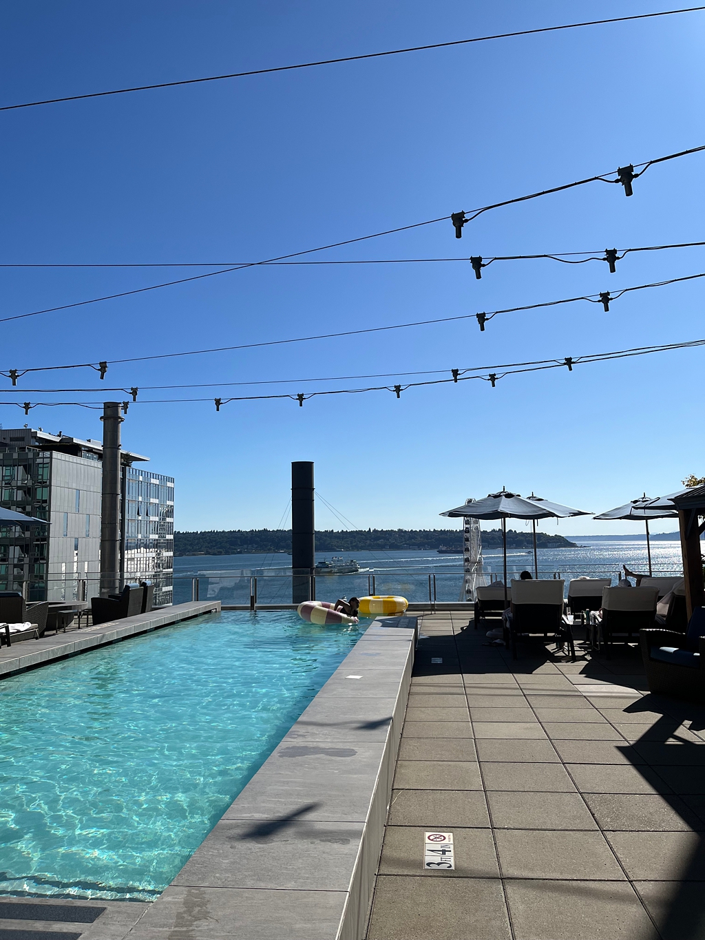 An image of the Four Seasons Seattle elevated pool deck with a ferry in the background